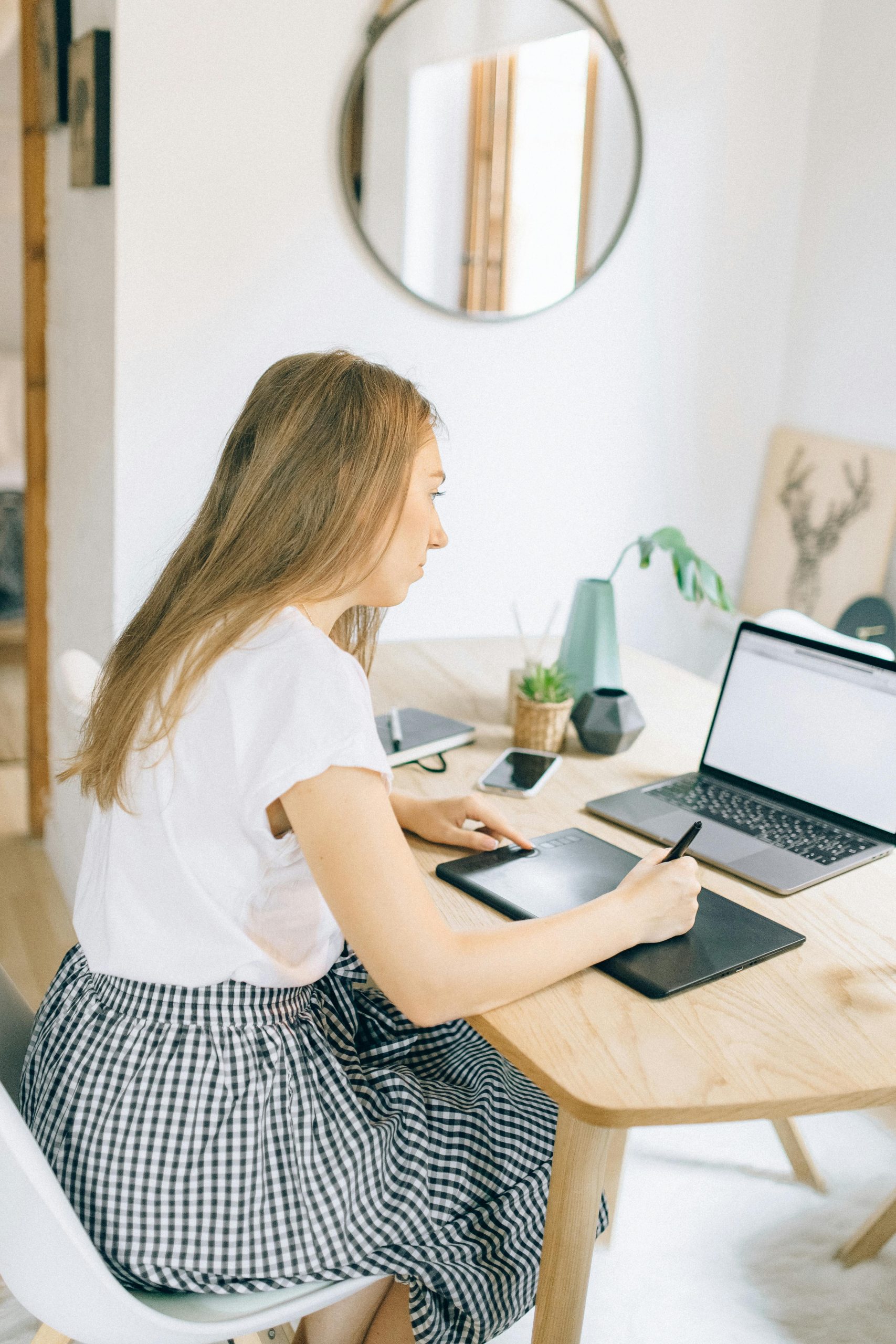 Woman working on laptop at home office desk, focusing on her work